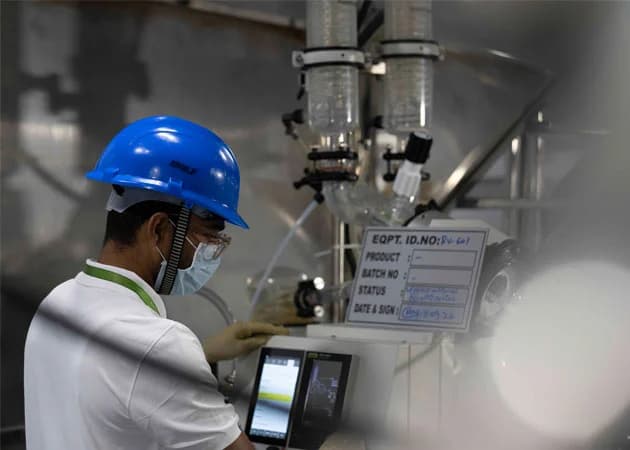 Two pharmaceutical scientists reviewing data on a tablet in a laboratory