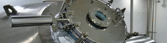 Stainless steel reactor vessel with a sight glass and manway cover in a commercial API manufacturing suite